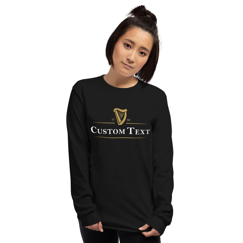 K&ouml;nnte beinhalten: Schwarzes Langarmshirt mit einem goldenen Harfenlogo und dem Text "CUSTOM TEXT" auf der Vorderseite.
