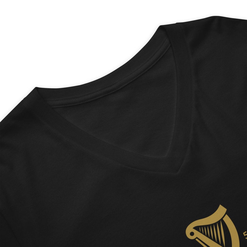 May include: Black V-neck t-shirt with a gold harp graphic.