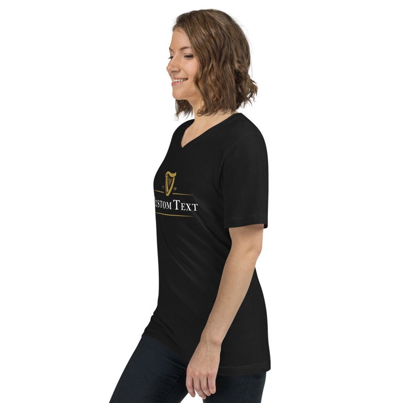 May include: Black V-neck t-shirt with a gold harp logo and the text "CUSTOM TEXT" printed on the front.