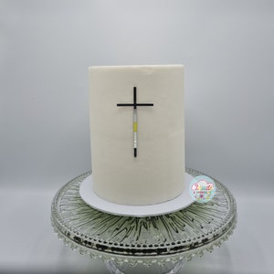A mirror silver acrylic crucifix charm stuck to the front of a cake