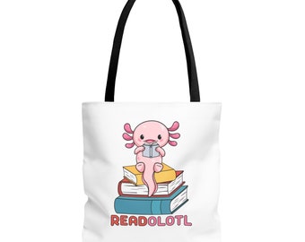 May include: A white tote bag featuring a pink axolotl sitting on a stack of books. The axolotl is holding a book and the text "READOLOTL" is printed on the bag.