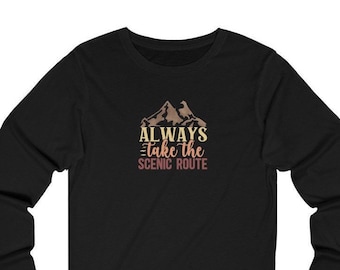 Op de afbeelding: Zwart shirt met lange mouwen met een bergafbeelding en de tekst "ALWAYS Take the SCENIC ROUTE" in retrostijl. Het ontwerp toont een bergketen in bruine en beige tinten, met tekst in geel en kastanjebruin.