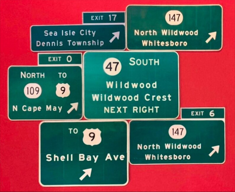 May include: A collection of green and white highway signs with arrows pointing in different directions. The signs include exit numbers, road names, and destinations such as Sea Isle City, Wildwood, and North Wildwood.