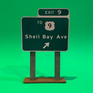 May include: Green highway sign with white text and a white arrow pointing to the right. The sign reads "Exit 9 To Shell Bay Ave".