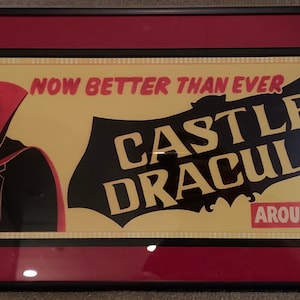 Könnte beinhalten: Ein Plakat im Vintage-Stil, das für "Castle Dracula" wirbt, mit dem Slogan "Now Better Than Ever Around Corner". Das Plakat zeigt einen Cartoon-Vampir mit einem roten Umhang und Fangzähnen vor einem gelben Hintergrund mit einer schwarzen Fledermaus-Silhouette.