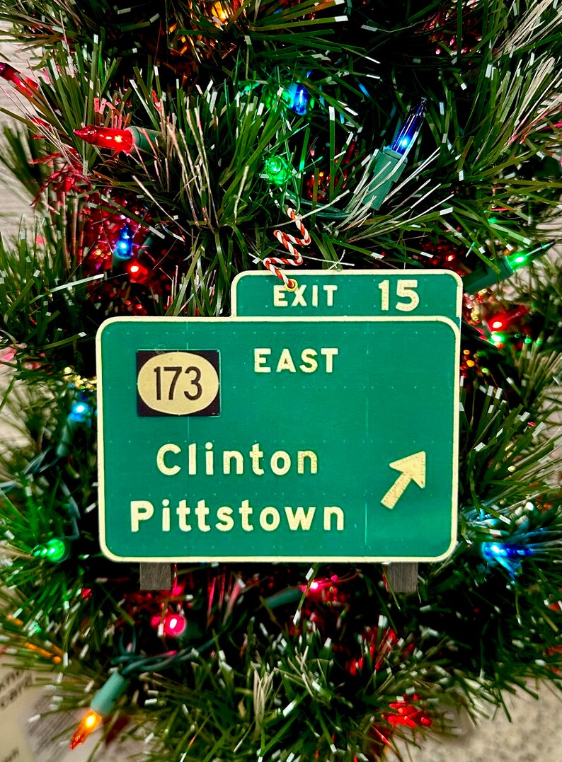 May include: Green highway sign with white text and a black circle with the number 173. The sign reads "Exit 15 East Clinton Pittstown" with an arrow pointing to the right.