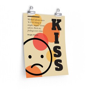 May include: A beige poster with a black and white illustration of a sad face with a red and yellow circle behind it. The text "KISS" is in large black letters on the right side of the poster. The text "Michael always says "K-I-S-S. Keep it simple, stupid." Great advice. Hurts my feelings every time. Dwight Schrute" is in black text on the left side of the poster.