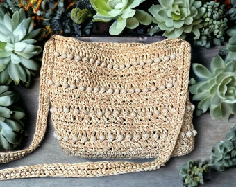 May include: A beige crocheted bag with a long strap. The bag is decorated with small white beads.
