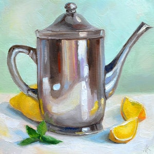 May include: A silver teapot with a lid and a spout, sitting on a white surface with three lemon slices and a sprig of green mint.
