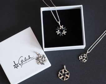 May include: Three silver necklaces with black and silver pendants in the shape of a Star of David. The necklaces are displayed on white boxes with the brand name "Gilich by Michael Gilchinski" printed on one of the boxes.