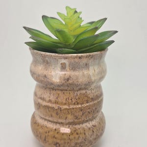 May include: A set of three ceramic mugs with a speckled, matte finish. The mugs are in shades of cream, light gray, and dark gray. Each mug has a simple, minimalist design, perfect for coffee or tea.