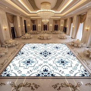 May include: A white dance floor with a blue and gray patterned design. The dance floor is in a large, white room with white chairs and tables arranged around the perimeter.