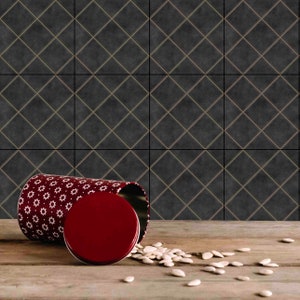 May include: A red and white patterned metal canister with a red lid is tipped over, spilling white seeds onto a wooden surface. The canister is sitting in front of a black and gold tiled wall.