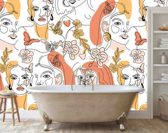 May include: A white bathroom with a bathtub and a white shelf unit. The wall behind the bathtub is covered in a wallpaper with a pattern of orange and yellow abstract faces, flowers, and butterflies.