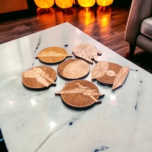 May include: Six wooden coasters featuring iconic spaceships from a popular science fiction franchise. The coasters are laser-cut with detailed designs of a Star Destroyer, Millennium Falcon, Death Star, TIE fighter, X-wing, and a Rebel transport ship.
