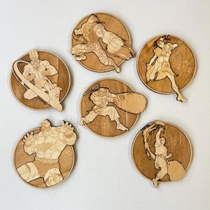 Puede incluir: Seis posavasos de madera con diferentes personajes de un videojuego. Cada posavasos es redondo y tiene un acabado de madera de grano marrón. Los personajes están dibujados en un estilo de dibujos animados y están en varias poses.
