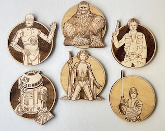 Könnte beinhalten: Sechs Untersetzer aus Holz mit Motiven aus Star Wars. Die Untersetzer sind rund und haben eine braune Holzoptik. Die Figuren sind Chewbacca, Prinzessin Leia, Han Solo, R2-D2, C-3PO und Luke Skywalker.