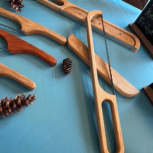 May include: Four wooden bread knives with a serrated blade and a wooden handle. The knives are on a blue surface.