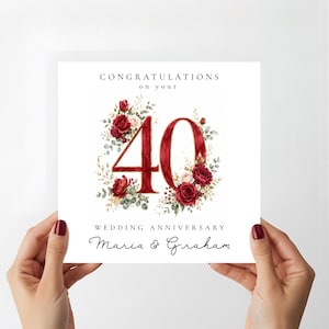 May include: A square white greeting card featuring the text CONGRATULATIONS ON YOUR 40 WEDDING ANNIVERSARY and the names Maria & Graham. The number 40 is decorated with watercolour illustrations of deep red roses and green eucalyptus foliage.
