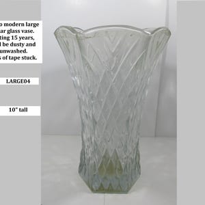 Puede incluir: Un jarrón retro de vidrio transparente con un patrón de diamantes, de aproximadamente 25 cm de altura. El jarrón tiene un borde ancho y festoneado y una base hexagonal. El texto en la imagen dice "Retro modern large clear glass vase." y "LARGE04".