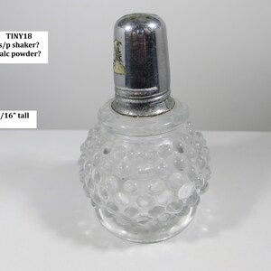 May include: A clear glass shaker with a silver metal lid. The shaker is 3-1/16" tall and has a textured, bubble-like pattern on the glass. The lid has a small decorative element. The text "TINY18 s/p shaker? talc powder?" is visible.
