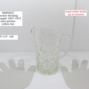 May include: Clear glass mini-pitcher with a pineapple pattern, yellow tint, and a handle. The pitcher is 5-1/4 inches tall. The text on the image says "SERVE27 Anchor Hocking Pineapple 1967-1975 mini-pitcher yellow tint."
