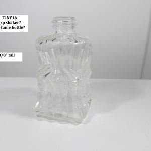 May include: A clear, faceted glass bottle, approximately 2-3/8 inches tall. The bottle has a square base and a textured, geometric design. The top of the bottle has a threaded opening. Text on the image reads: TINY16 s/p shaker? perfume bottle?