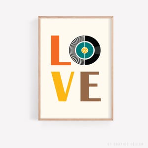 May include: A framed art print with the word "LOVE" in bold, colorful letters. The "L" is orange, the "O" is a vinyl record graphic, the "V" is yellow, and the "E" is brown. The background is off-white.