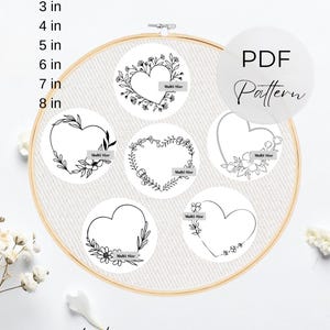 Puede incluir: Un conjunto de 6 patrones de bordado PDF imprimibles con diseños de corazones florales. La imagen muestra un bastidor de madera con tela blanca y cinco motivos de corazones en línea negra. Texto: "EACH 2 in 3 in 4 in 5 in 6 in 7 in 8 in", "FLORAL HEARTS", "PDF Pattern", "Multi Size" y "Printable Hand Embroidery Patterns".