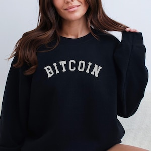 May include: Black sweatshirt with the word "BITCOIN" in white lettering in an arch shape.