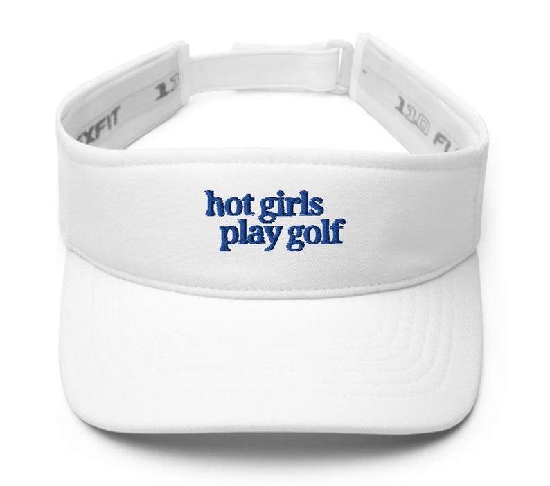 May include: White visor with the embroidered text "hot girls play golf" in blue. The visor has a curved brim and an adjustable strap. The text is in a playful, casual font.