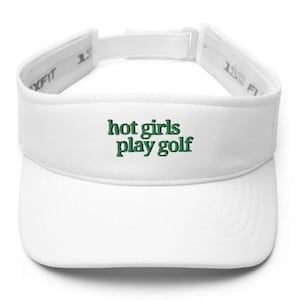 May include: A white visor with the embroidered text "hot girls play golf" in green. The visor has a curved brim and an adjustable strap. The visor is designed to shield the eyes from the sun.