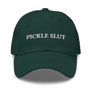 May include: A dark green baseball cap with the text "PICKLE SLUT" embroidered in white on the front.