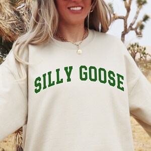 May include: A beige sweatshirt with a green "SILLY GOOSE" graphic in a collegiate font.
