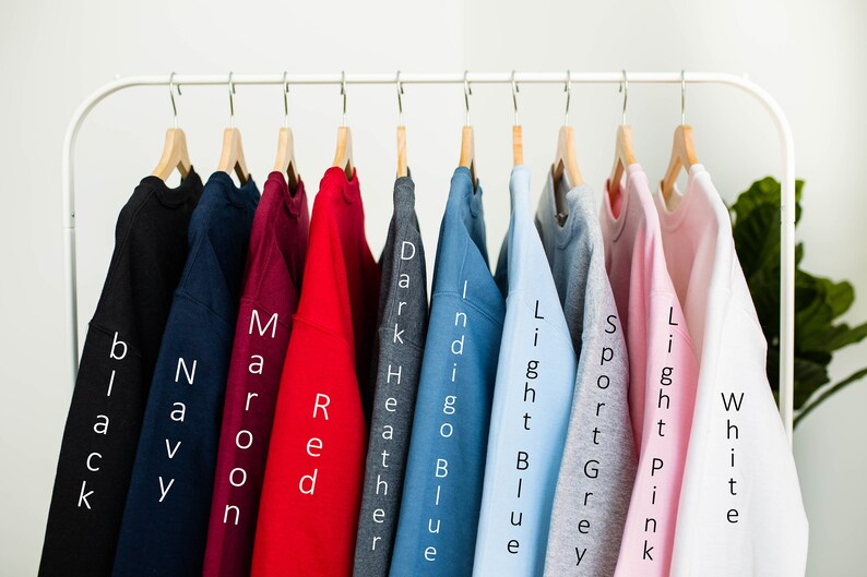 May include: Ten different colored sweatshirts hanging on a rack. The colors are black, navy, maroon, red, dark heather, indigo blue, light blue, sport grey, light pink, and white.