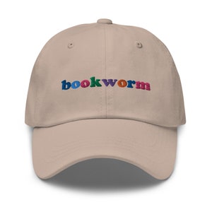 May include: A beige baseball cap with the word "bookworm" embroidered in colorful letters.