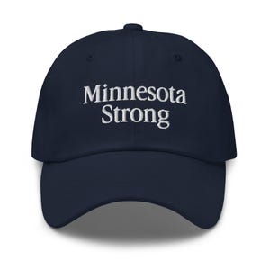 May include: Navy blue baseball cap with the embroidered text "Minnesota Strong" in white. The cap has a curved brim and a fabric-covered adjustable strap at the back.