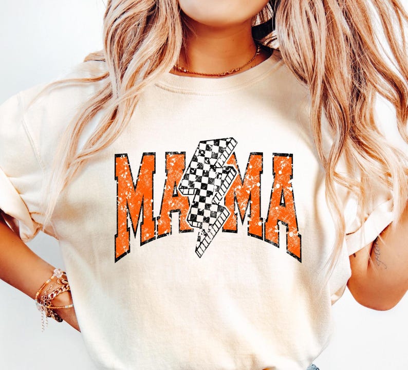 K&ouml;nnte beinhalten: Ein wei&szlig;es T-Shirt mit einer orangefarbenen Grafik, auf der "MAMA" mit einem karierten Blitz in der Mitte steht.