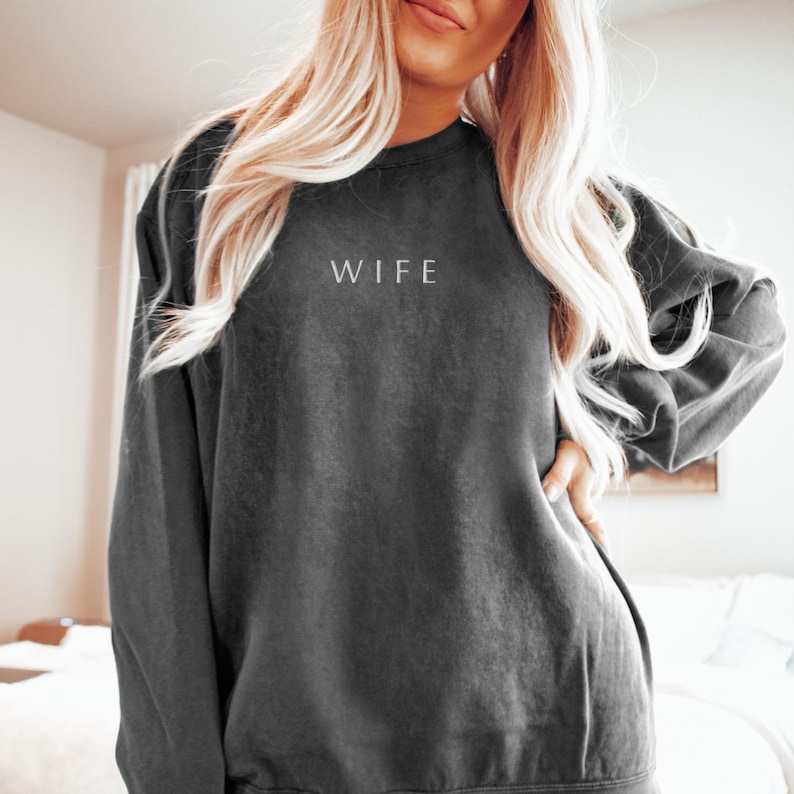 May include: A dark grey sweatshirt with the word "WIFE" printed in white on the front.
