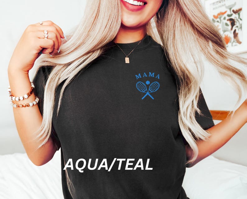 May include: A black t-shirt with the text "MAMA" and a blue tennis racket and ball graphic. The text "AQUA/TEAL" is printed below the graphic.
