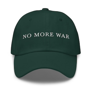 May include: A dark green baseball cap with the white text "NO MORE WAR" embroidered across the front. The cap has a curved brim and a button on top. This hat is a statement piece.
