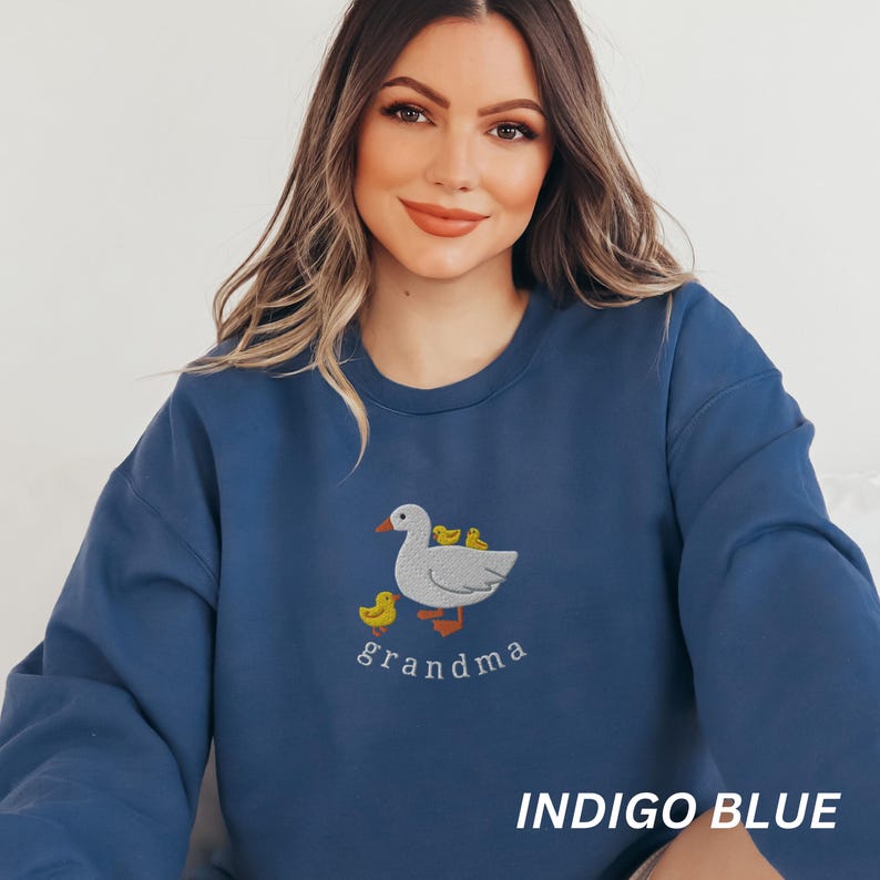 May include: Indigo blue sweatshirt with an embroidered image of a white duck with yellow ducklings and the word "grandma" underneath.