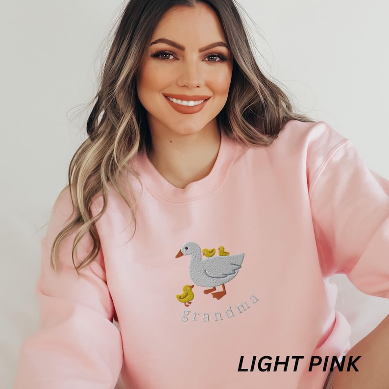 May include: Light pink sweatshirt with an embroidered goose and goslings design and the text "grandma".