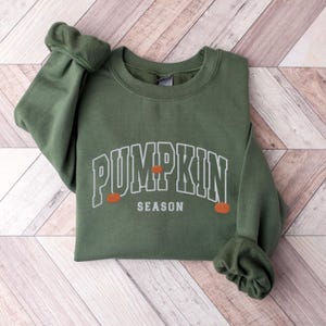 May include: A green sweatshirt with the text "Pumpkin Season" in white outlined letters with three orange pumpkins.