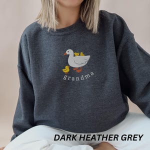 May include: Dark heather grey sweatshirt with an embroidered design of a goose with three chicks and the word "grandma".