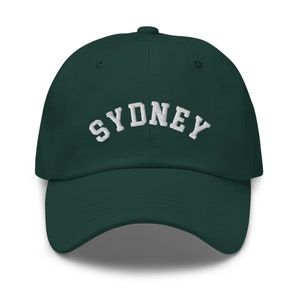 May include: A dark green baseball cap with white embroidered text that reads "SYDNEY".