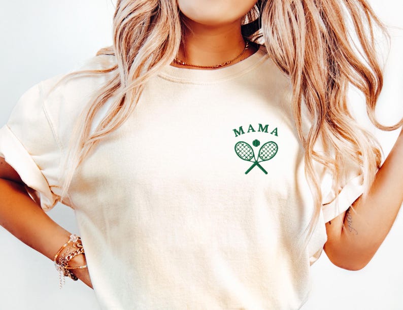 May include: A white t-shirt with a green tennis racket and ball graphic and the text "MAMA" on the front.