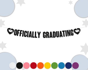 May include: A black banner with the words "OFFICIALLY GRADUATING" in bold white letters. The banner has a heart shape with a graduation cap on each end. A row of colorful felt circles is at the bottom.