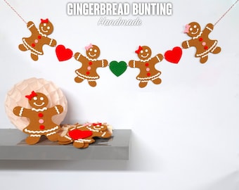 May include: Gingerbread bunting with red hearts and a green heart, handmade. The bunting is strung with red and white twine. The gingerbread people are brown with white icing and pink bows.