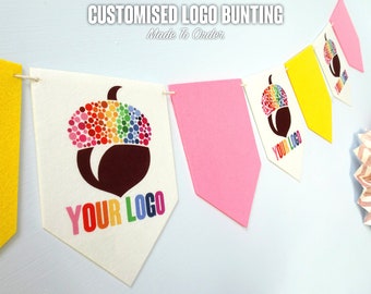 May include: A white bunting with a colorful acorn design and the text "YOUR LOGO" on each flag. The bunting is made to order and can be customized with your own logo.